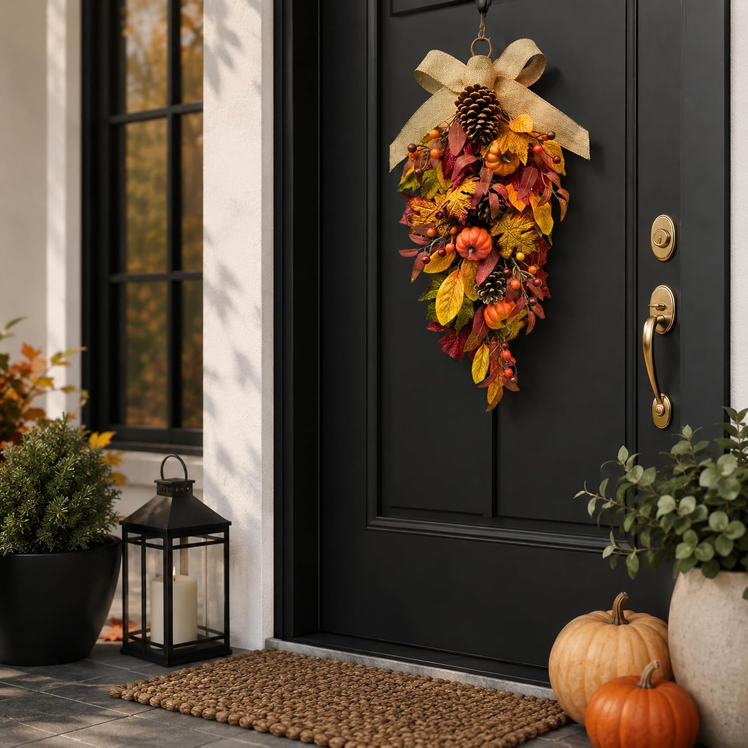 Pumpkin and pinecone fall swag displayed on a black front door